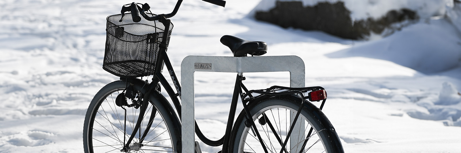 A bike attached to a bicycle stand in snowy weather.